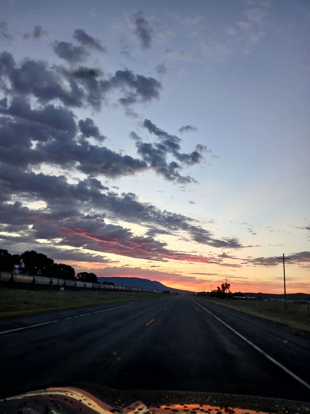 A Montana highway leading toward a glowing sunset.
