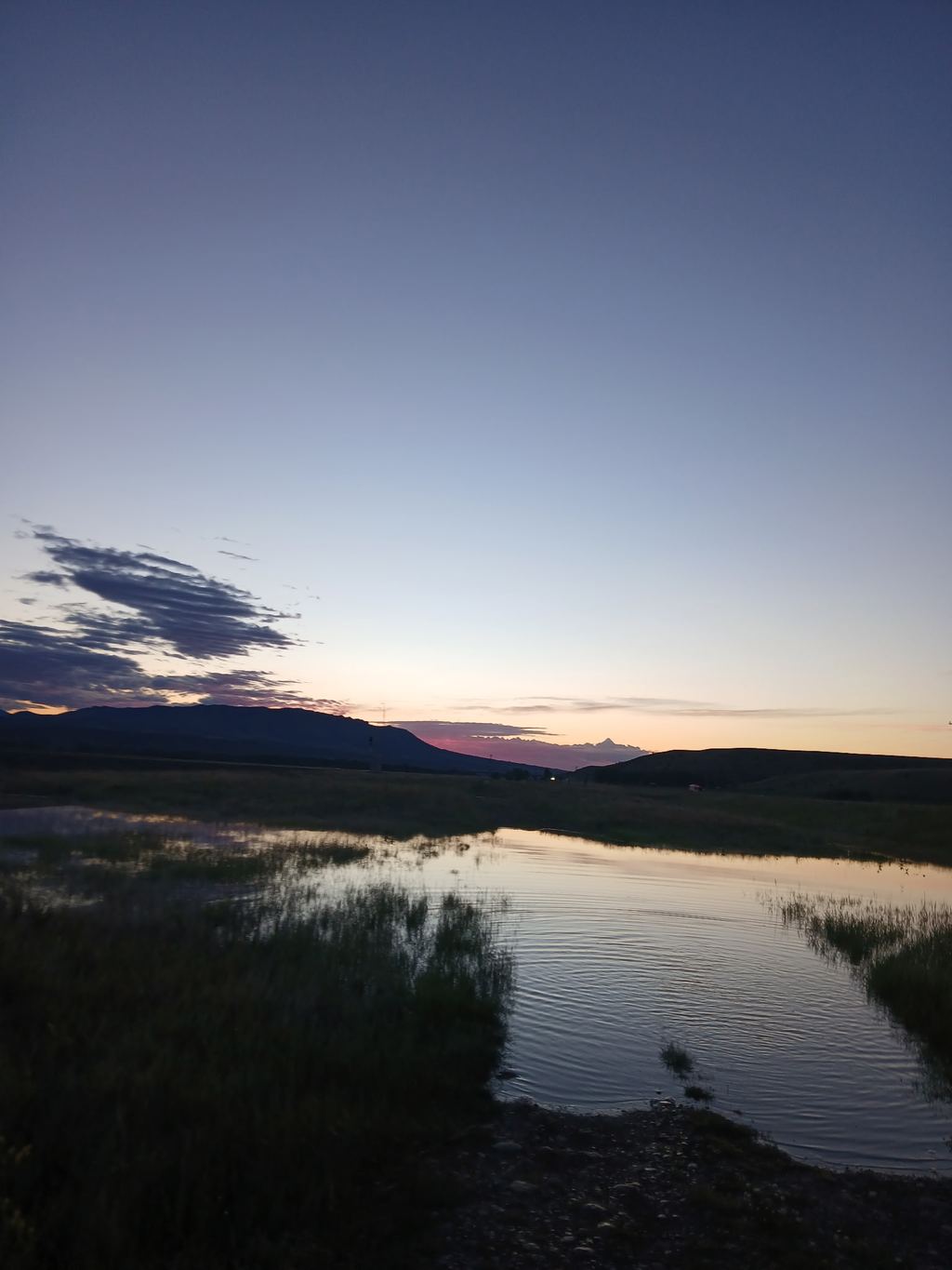 Soft dusk light reflected in water below Montana hills.