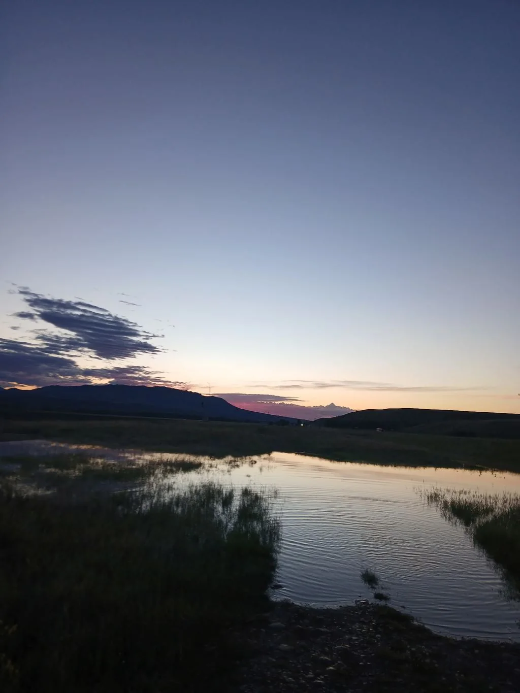 Soft dusk light reflected in water below Montana hills.